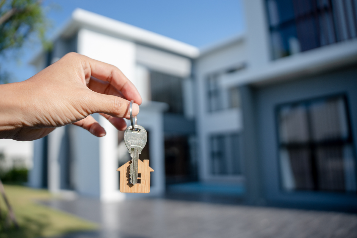 picture of a person holding keys infront of a home symbolizing tips to them buying a home